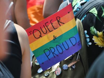 a rainbow flag that says queer and proud attached to a backpack
